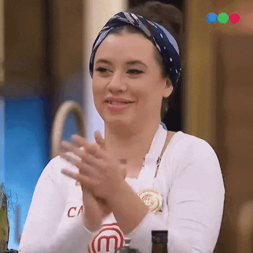 a woman wearing a white shirt with the letter m on it applauds
